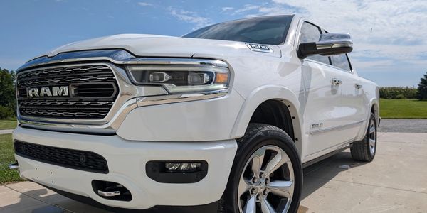 White RAM truck parked on a driveway under a bright sky.