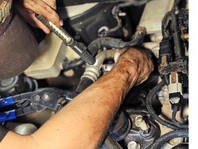 Mechanic performing engine diagnostics on vehicle wiring and components