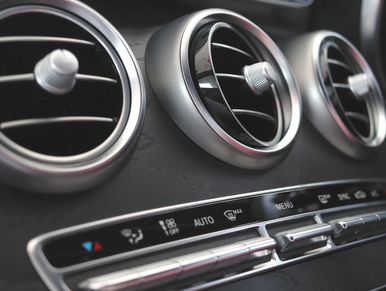 Car air-conditioning vents and climate controls during A/C system check and re-gassing.