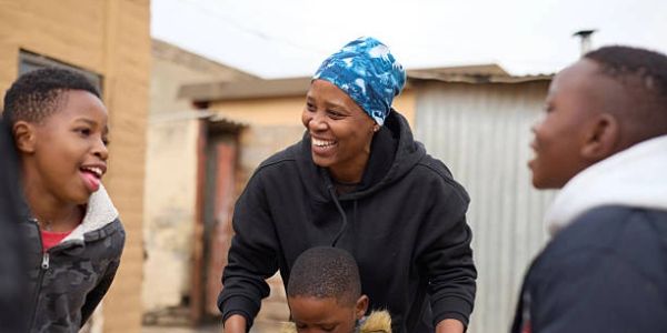 A joyful woman and children outdoors sharing laughter.