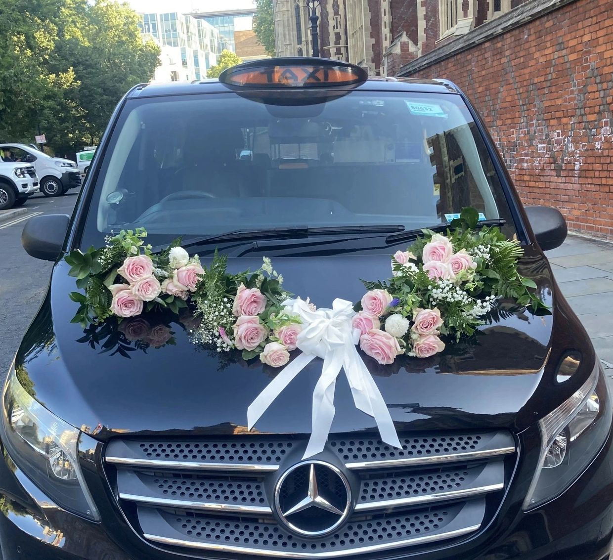 Black Mercedes taxi decorated with pink roses and white ribbon.