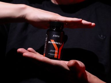 Man holding JOYOU Burn Max supplement between hands, symbolizing energy and weight management.