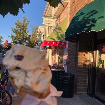 A satisfied customer taking a picture of their ice cream with our exterior in the background.
