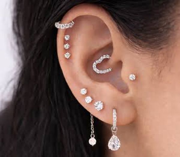 Ear adorned with multiple diamond earrings.