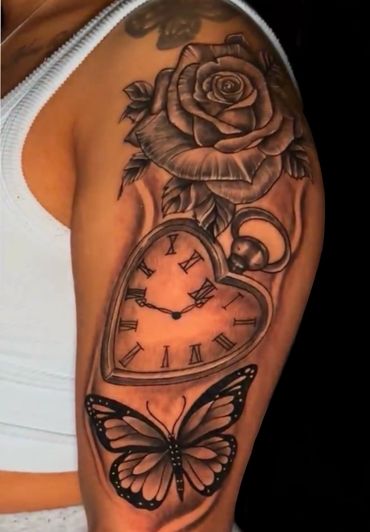 Tattoo of a rose, pocket watch, and butterfly on an arm.