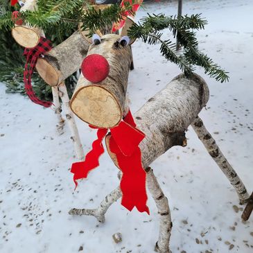 Handcrafted birch wood reindeer with a red bulb nose, evergreen antlers and a Christmas bow tie
