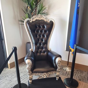 Black and silver throne chair placed in a roped-off display area beside the Nevada state flag for public or VIP event setup.