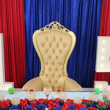Gold tufted throne at a vibrant 15th birthday setup with blue sequin tablecloth and floral decorations.