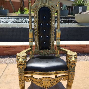 Black and gold throne chair with lion armrests and tall backrest placed outdoors near a modern water feature for upscale seating at a luxury Las Vegas venue.