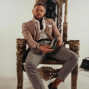 Black and gold lion-arm throne with tall backrest used in a professional indoor photoshoot for celebrity or promotional branding display.