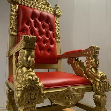 Gold square throne with detailed face carvings and red padding photographed indoors for luxury rental showcase.