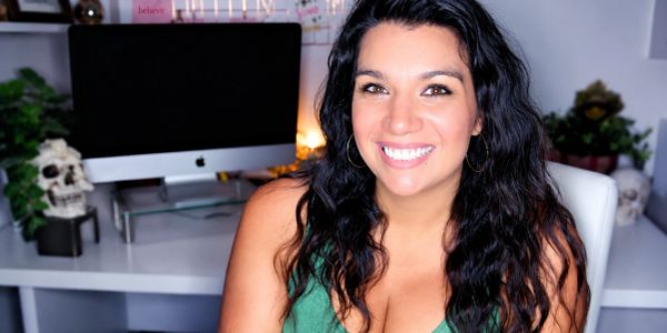 Smiling woman with long dark hair in front of a computer.