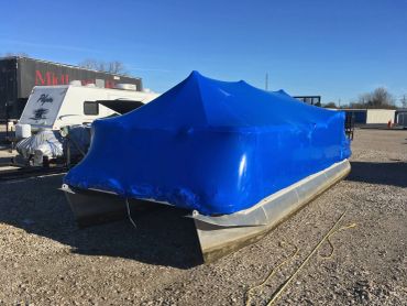 Pontoon boat covered with blue shrink wrap.