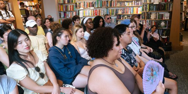 A diverse group attentively listens in a bookstore.