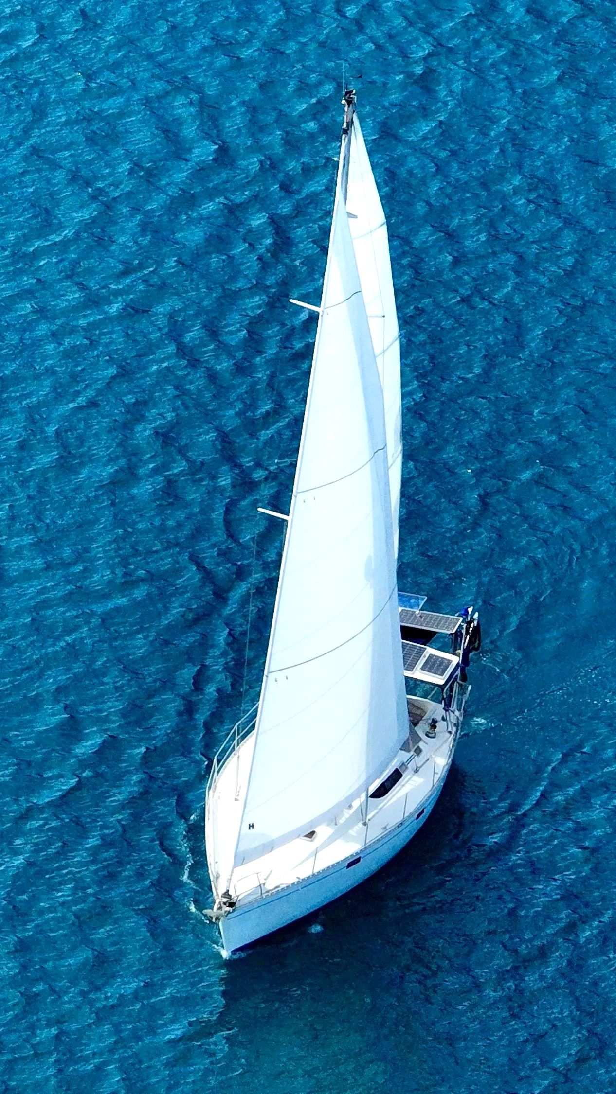A white sailboat gliding on deep blue water.