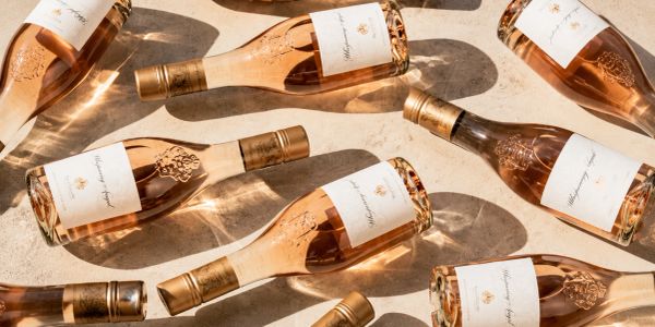 Several bottles of rosé wine arranged on a sunlit surface.