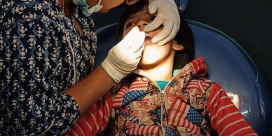 A child receiving dental care from a dentist wearing gloves.