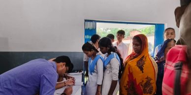 People standing in line inside a room, some signing documents.
