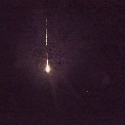 Bright streak of a meteor falling in the night sky.