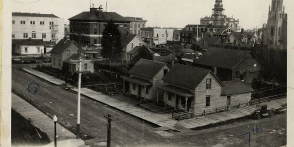 Historic black and white photo of early 20th-century houses and buildings at a street corner.