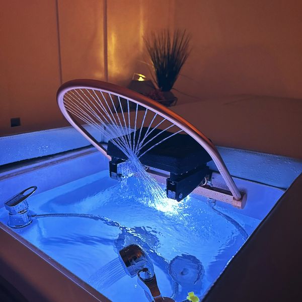 A modern bathtub with blue LED lighting and water jets.