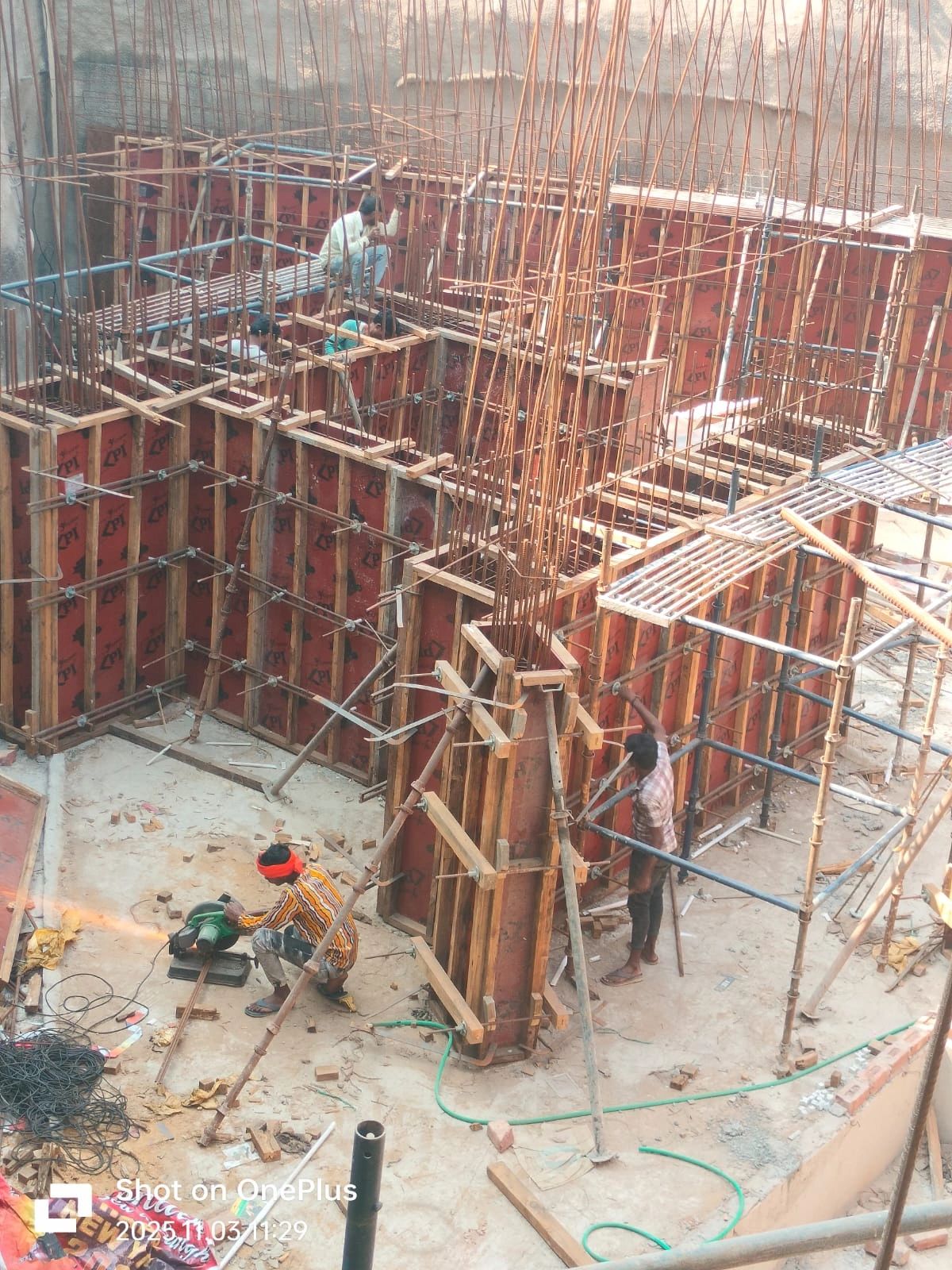 Construction workers building reinforced concrete walls with steel rods and scaffolding.