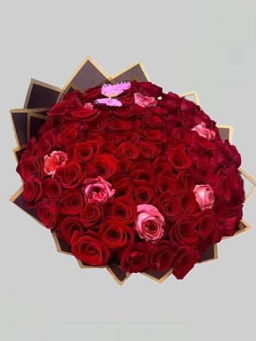 A bouquet of red roses with a few pink roses and a purple butterfly.