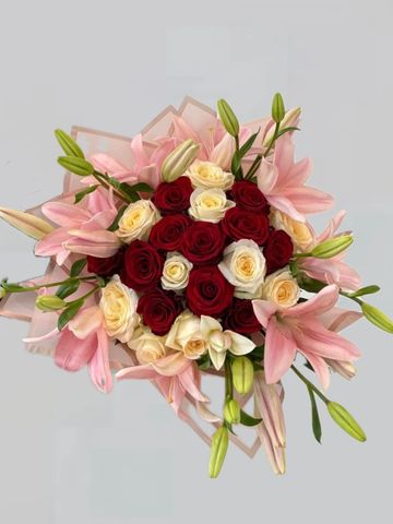 Elegant bouquet with red and cream roses surrounded by pink lilies.