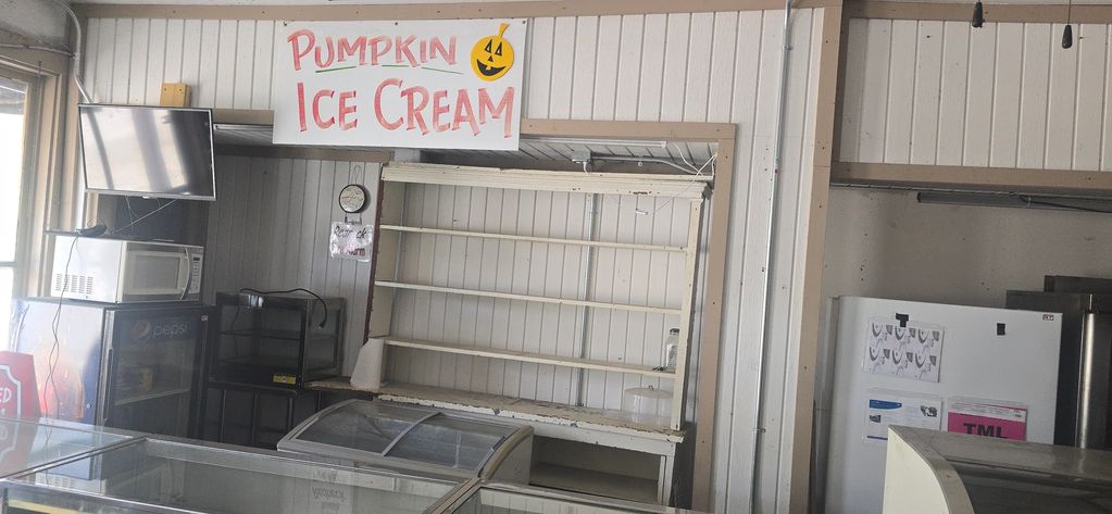 Empty ice cream display with a Pumpkin Ice Cream sign above it.