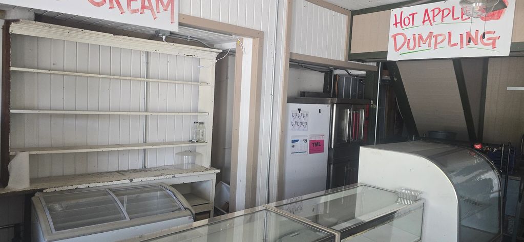 Empty food display shelves and counters under signs for ice cream and hot apple dumplings.