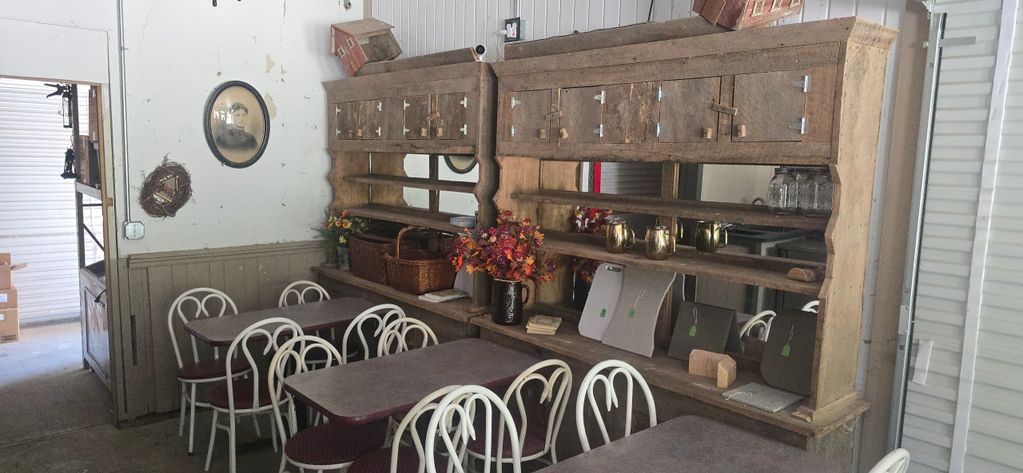 Rustic dining area with vintage wooden shelves and white chairs.