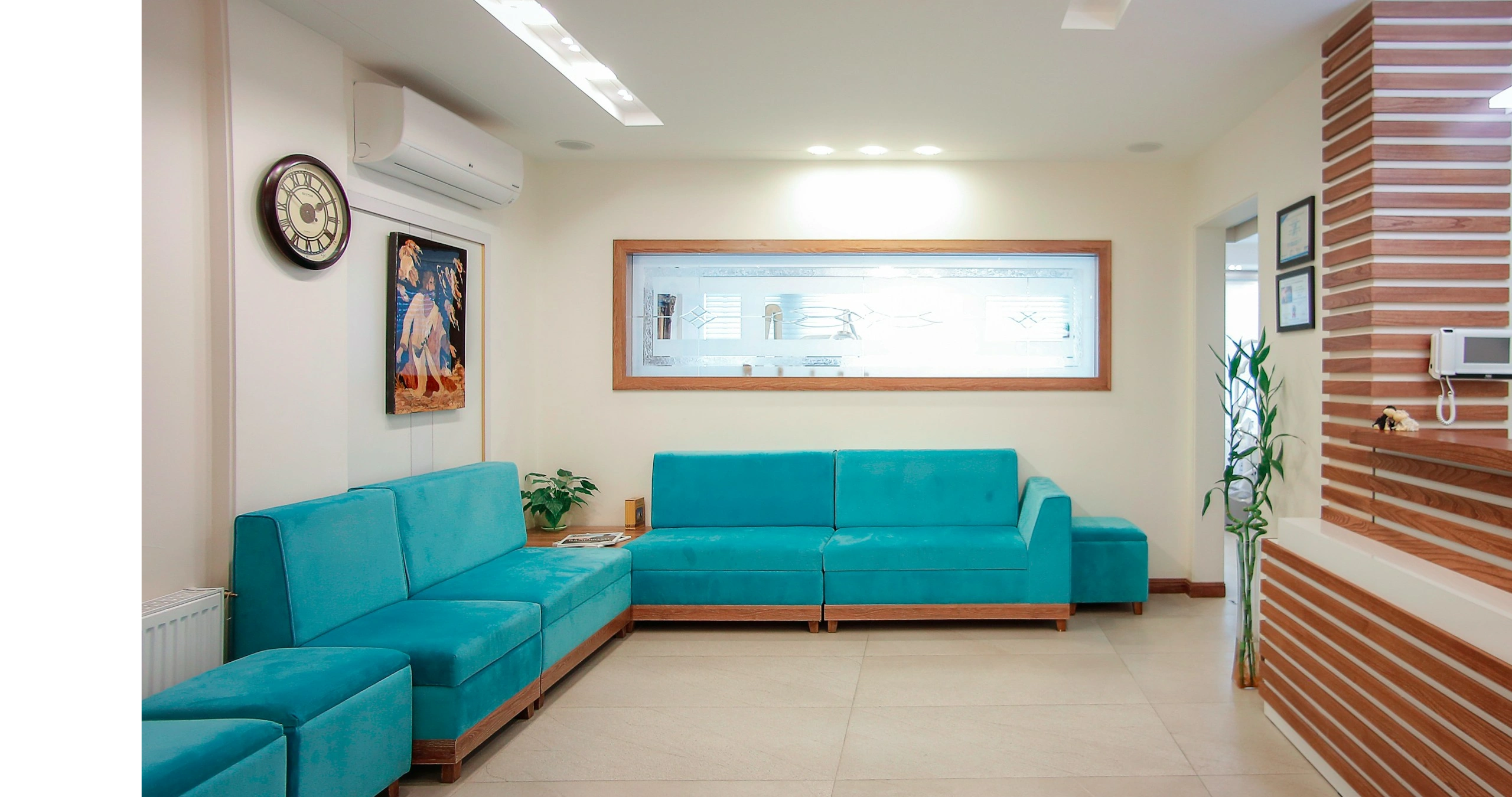 Bright waiting room with turquoise sofas and wooden accents.