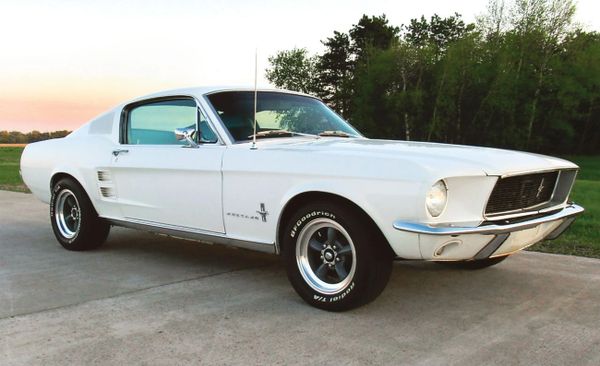 Classic white 1967 Ford Mustang parked on a driveway at sunset.