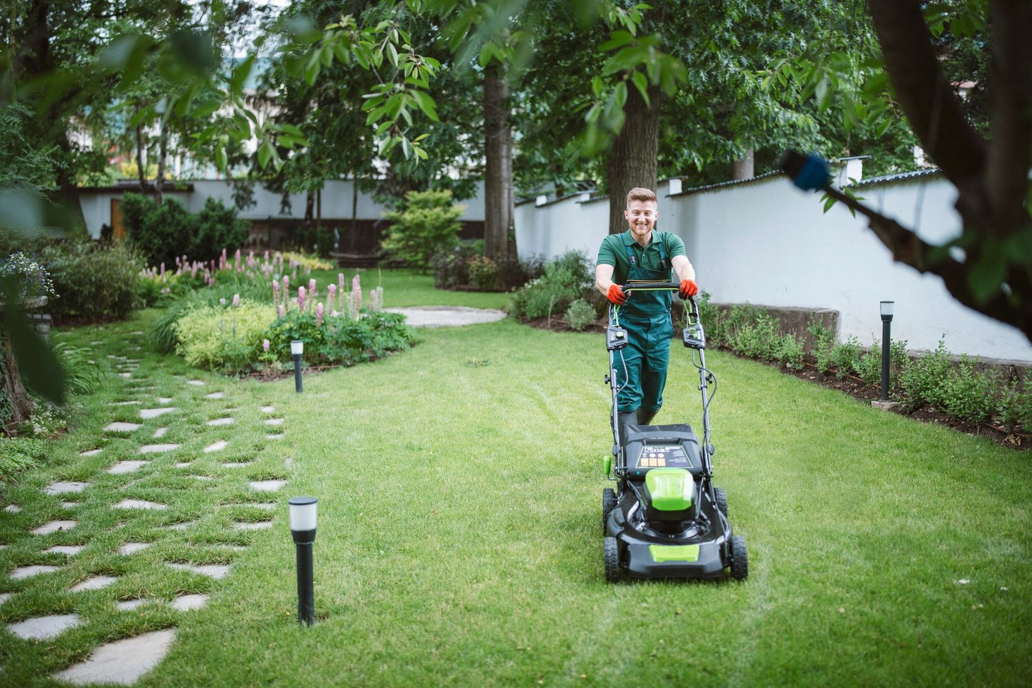 Man mowing a green lawn.
