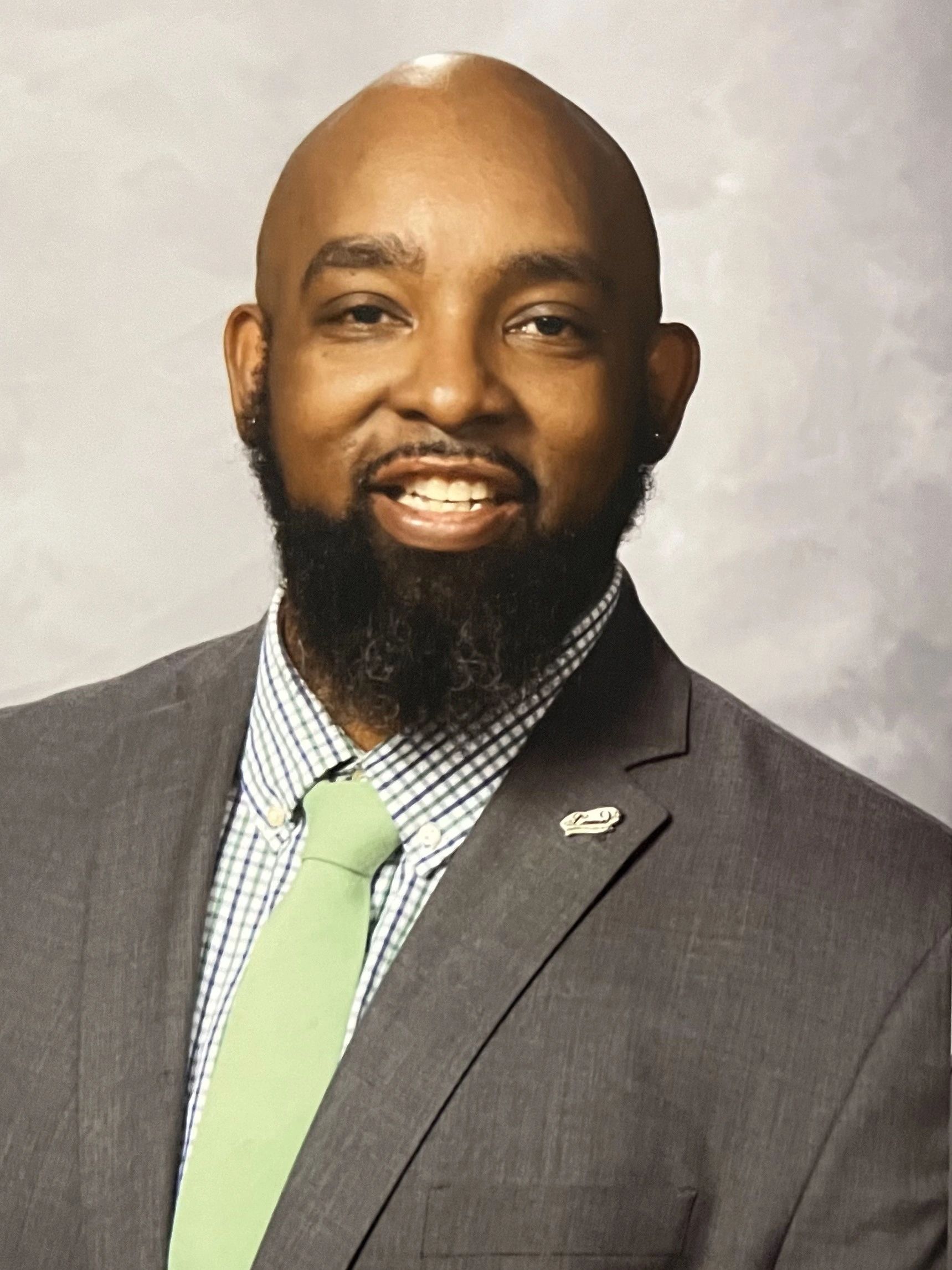 A smiling bearded man in a suit and green tie.