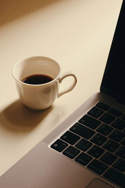 A cup of coffee next to a laptop keyboard.