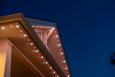 House roofline decorated with red and white lights at night.