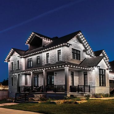 Elegant two-story house with bright white LED lights outlining the roof against a night sky.