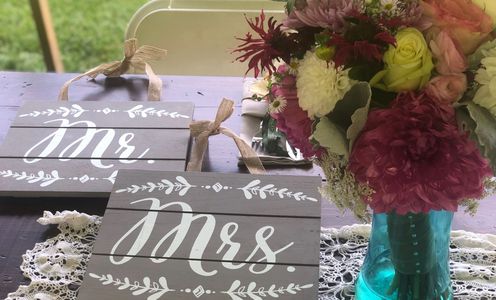 Mr. and Mrs. wood signs next to blue vase with brides bouquet. 