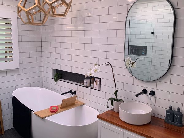 Contrasting white subway tiles and black grout. A freestanding bath  with a recessed niche and wall
