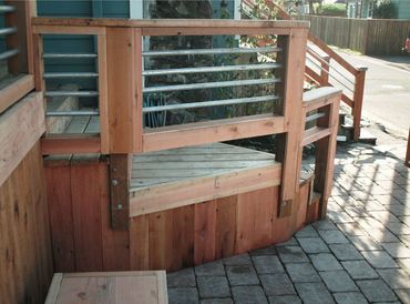 Wood deck with steps, banister with metal accents, Patio with brick paving stones.