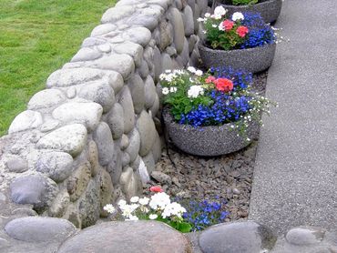 Landscape with stone pots full of flowers a stone wall