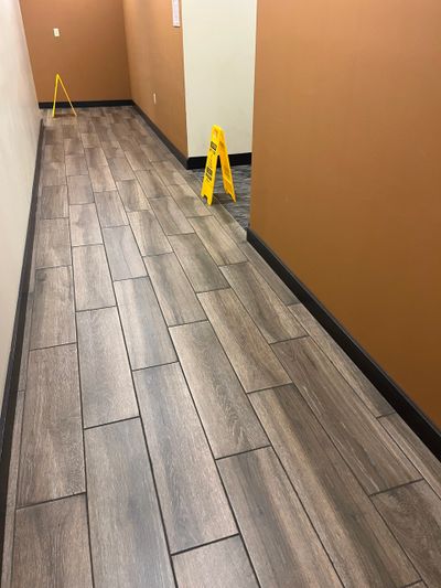 Hallway with wood-patterned tile floor and caution signs.