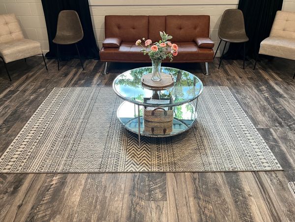 Modern living room with brown sofa, patterned rug, and glass coffee table.