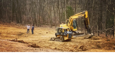 Contractor discussing site preparation for new home.  Excavator and skid steer clearing land