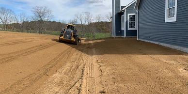Skid steer completing final grade on new construction home. Excavating and grading for new home
