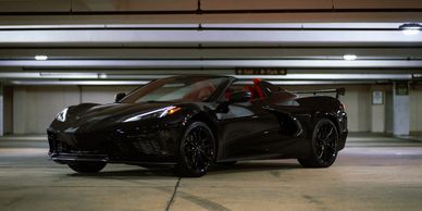 Sleek black sports car parked in an underground garage.