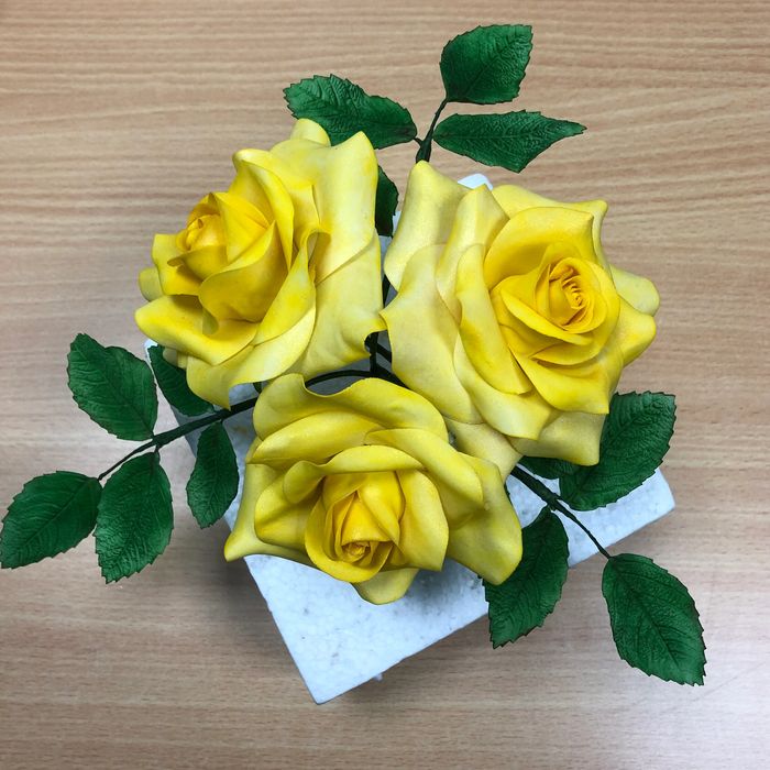 3 large yellow roses with rose leaves