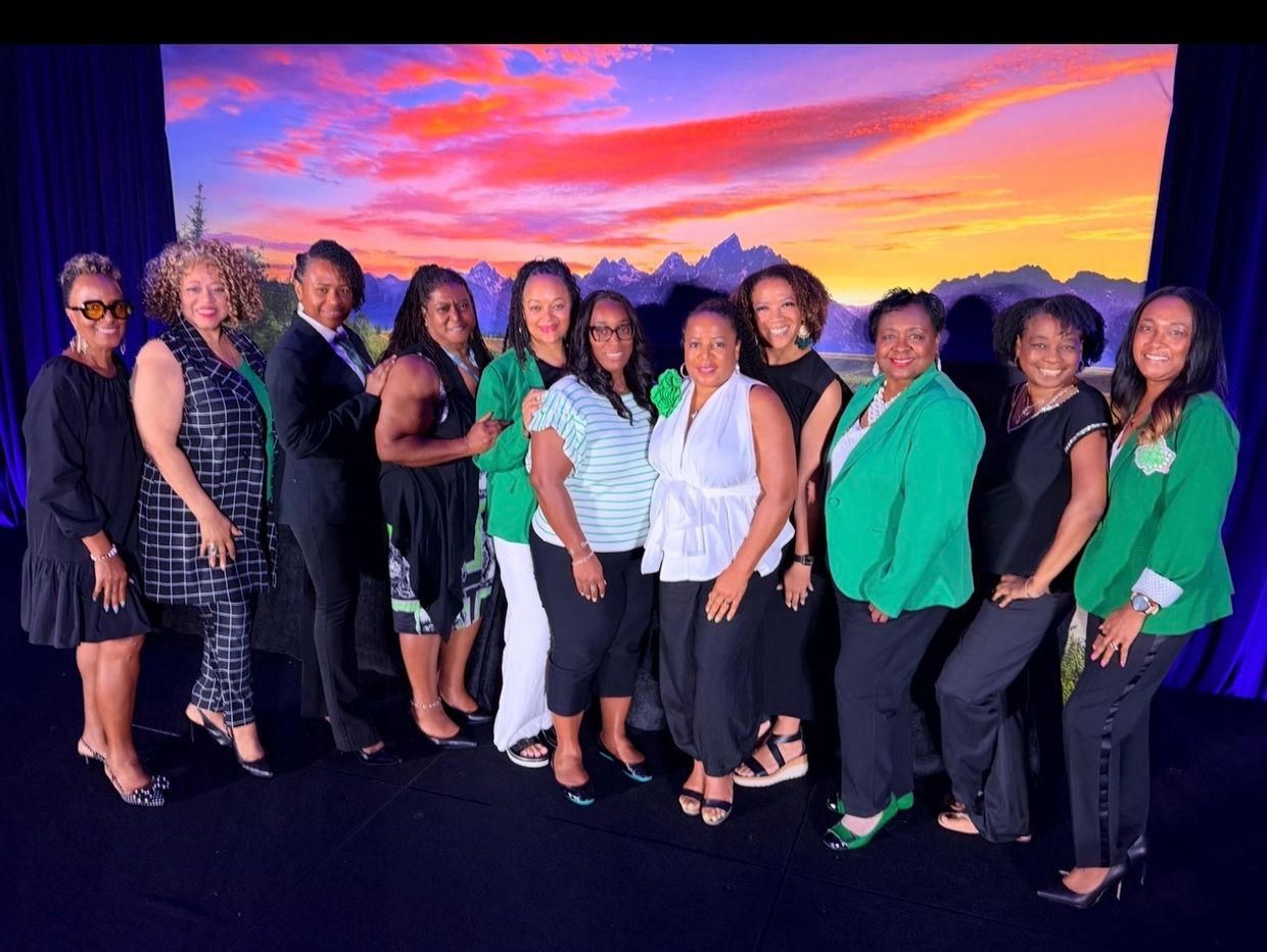 Group of women smiling against a sunset backdrop.