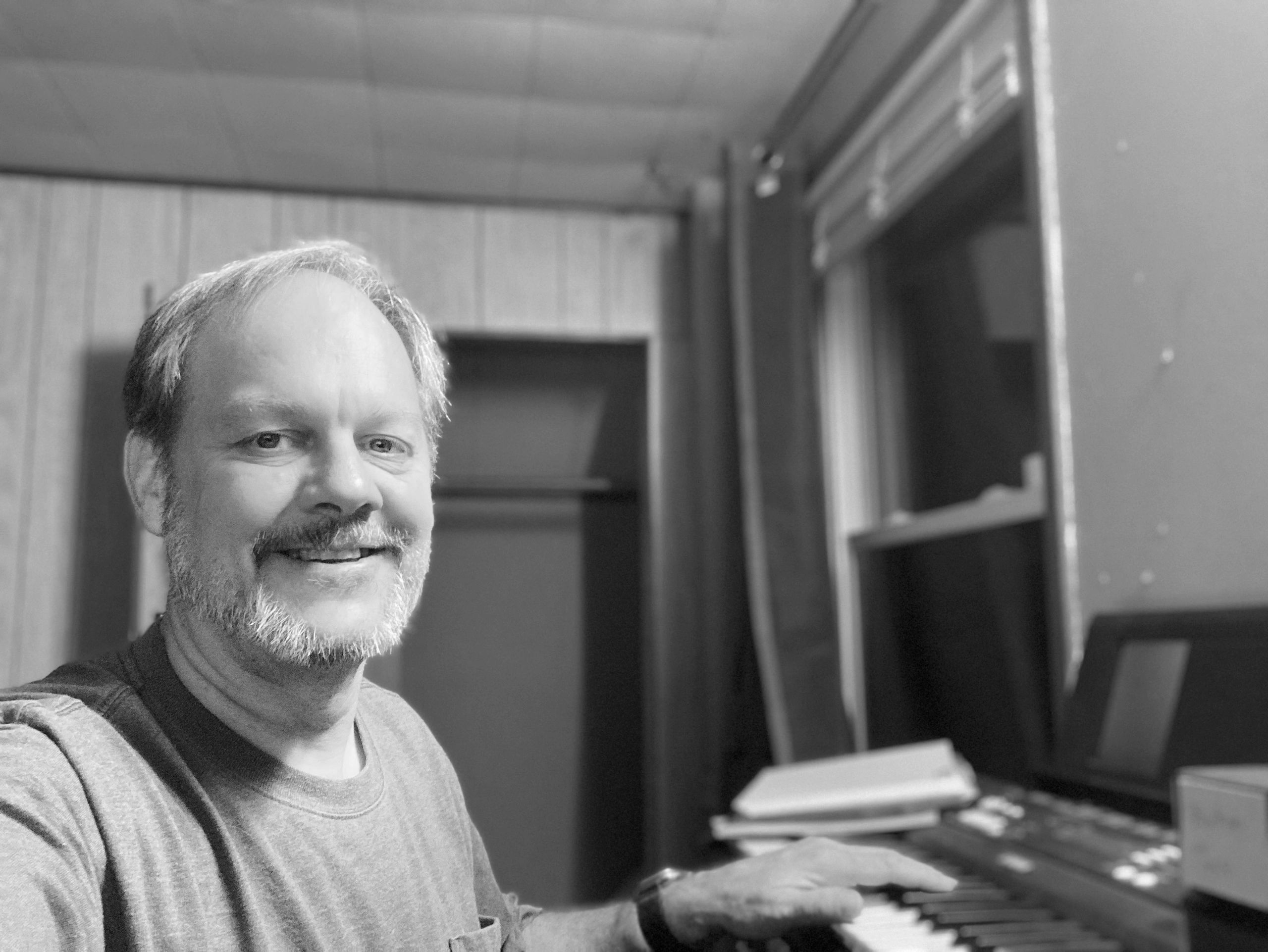 black and white picture of author and publisher charlie cj sitting at a keyboard